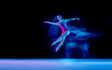 Fototapeta na wymiar Ghost. Young and graceful ballet dancer on black studio background in neon mixed light. Art, motion, action, flexibility, inspiration concept. Flexible caucasian ballet dancer, weightless jumps.