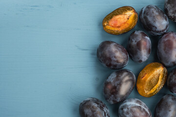 Ripe plums on wooden blue table. Autumn harvest. Top view, copy space