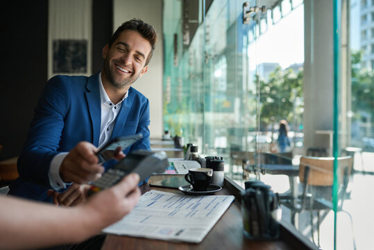 Smiling man paying his cafe waiter using nfc technology - Powered by Adobe