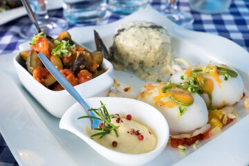 Delicious seafood restaurant dish from French cuisine - stewed calamari served with tomato and orange salsa, vegetable ratatouille, rice and catch of the day - mussels 
