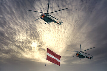 Helicopter carrying gigantic the national flag of Latvia. A military parade dedicated to the...
