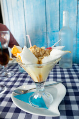 Delicious meringue cake made of whipped egg whites and served with caramel and liquor syrup, a ball of vanilla ice-cream, fruit and sliced almonds in Gruissan, France