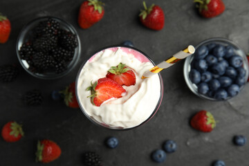 Tasty milk shake with whipped cream and fresh berries on black slate table, flat lay