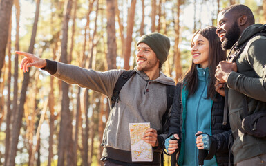 Happy hikers found right way, holding map at forest