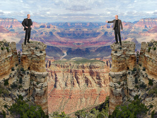 Two men isolated on rock silos with a Grand Canyon chasm separating them © Reimar
