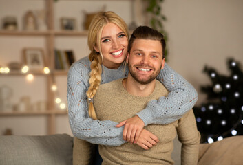 Joyful man and woman cuddling at home during xmas eve