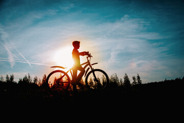 Obraz premium happy kid riding bike at sunset nature