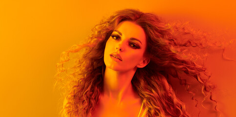 Fashion. Woman in colorful neon gold light, make-up. Beautiful blond girl, stylish curly hair, trendy makeup. Golden portrait. Creative beauty, fashionable model face, voluminous hairstyle