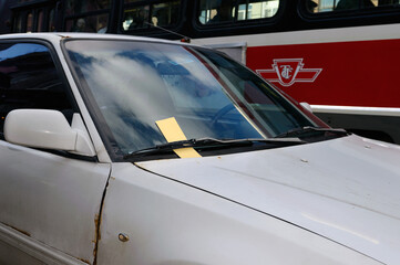 Obraz premium Bilet w przedniej szybie jalopy, gdy przejeżdża czerwony tramwaj