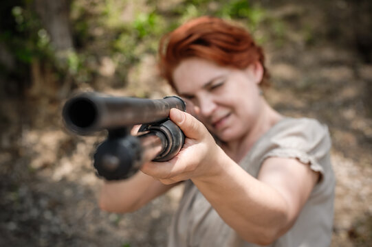 Woman shooting with pump gun. Direct macro detail close-up shotgun front view gun point. Firearm shooting and weapons training. Shooting range