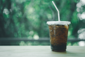 Soft drink in plastic glass with green nature background