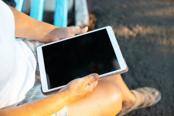 Close up of woman's hand woman uses digital tablet devicet in the park outdoors.