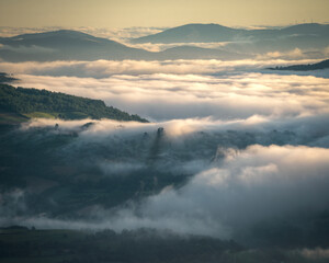 Fototapeta premium Misty sunrise alternating forested mountains and green valleys