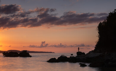 Naklejka na ściany i meble Rocks in the Mediterranean Sea backlit by the sunset
