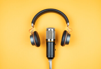 podcasting concept, directly above view of headphones and recording microphone on orange background - obrazy, fototapety, plakaty