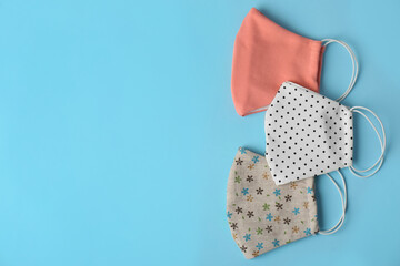 Homemade protective face masks on light blue background, flat lay. Space for text