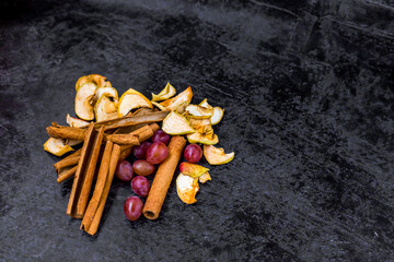 
Dried fruits, cinnamon sticks and grapes on the left side of the horizontal frame with space for text.