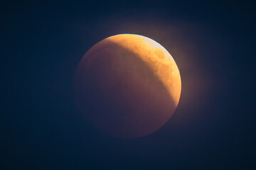 Red or blood moon, hazy full moon eclipse in 2018. Astronomical picture of red moon in an eclipse phase with sun just starting to dissappear from the right.