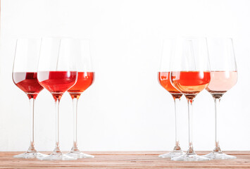 Rose wine glasses set on wine tasting. Tasting different varieties, colors and shades of pink wine concept. White background