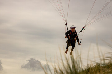 Naklejka na ściany i meble woman flying paraglider in Netherlands dunes