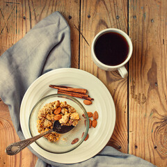 Fruits and nuts crumble pie server in a glass bowl and cup of black tea or coffee on a wooden table. Healthy dessert or autumn morning breakfast concept. Top view
