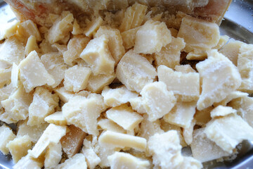 Big tray with Parmesan cheese chunks ready to be served or used for cooking. Delicious Italian traditional aged cheese, sharp hard dairy product, shredded o grated, eaten fresh or used as ingredient.