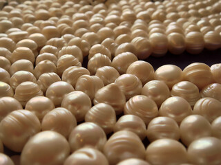 Close-up shot of freshwater cultured ringed pearls in ivory cream color with a fair, medium lustre, set on a table and thread on strings for necklaces and bracelets or other custom jewelry creations