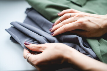 Cropped view of designer holding fabric on grey surface 