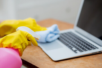 Hand of young asian woman cleaning and wipe laptop computer with disinfect and alcohol for protect pandemic covid-19 at home, girl in gloves cleaner notebook for hygiene, health care concept.