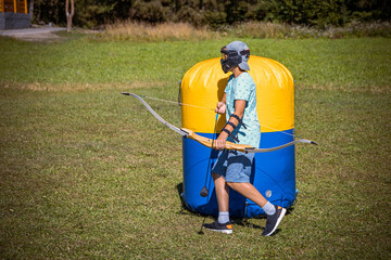 Young boy preparing to shoot arrow during a game of archery tag