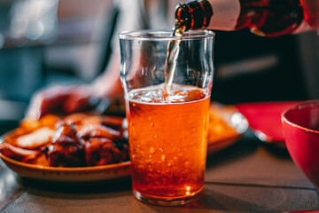 pouring beer in glass from bottle on bar or pub