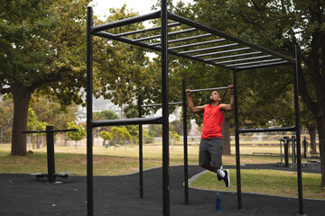 Black African American Man with prosthetic leg performing pull up exercise in the park