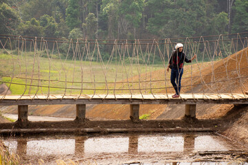 Travelers thai women visit walking on wooden suspension bridge in Pang Ung lake in Pang Oung forest park or Switzerland of Thailand in authentic Chinese village Ban Rak Thai in Mae Hong Son, Thailand