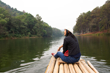 Travelers thai women travel visit and sitting relax on rowing bamboo rafts on Pang Ung lake in Pang Oung or Switzerland of Thailand in authentic Chinese village Ban Rak Thai in Mae Hong Son, Thailand