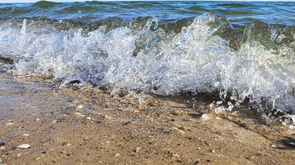 Seascape. Azure color of water, waves foaming on the shore. Selective focus. Summer rest.