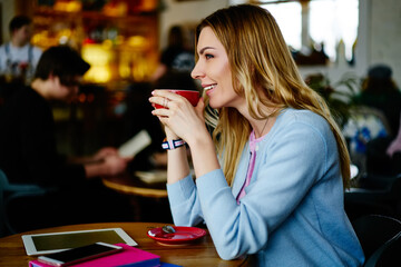 Cheerful woman drinking coffee in cafe