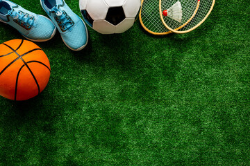 Sport games equipment on football field - balls, sneakers, rackets. Top view
