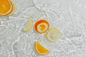Flatlay of transparent rippling water with orange and lemon slices © lavrenkova