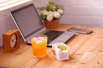 Eat sandwich and orange juice. During work with laptop computer. Work and eat food at the same time. Work at home.
