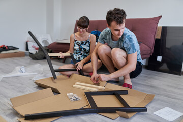 Young couple assembling their furniture