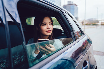 Focused young brunette with smartphone in  car