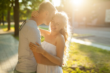 Happy and young pregnant couple hugging in nature