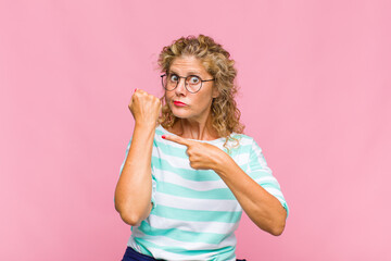 Middle age woman looking impatient and angry, pointing at watch, asking for punctuality, wants to...