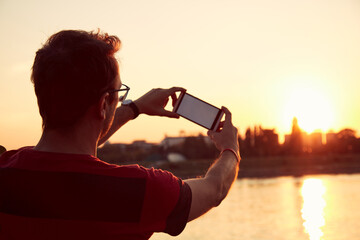 Fototapeta na wymiar Man holding a cellphone near the river.