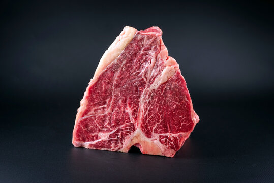 Raw dry aged wagyu porterhouse beef block offered as close-up on black background with copy space