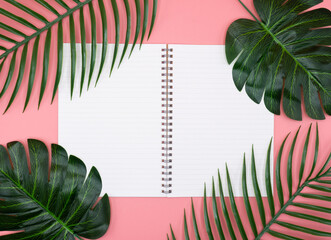 empty white diary book what has copy space which is decorated with plant leaves on the pink background