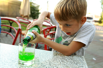Boy pouring green lemonade from bottle