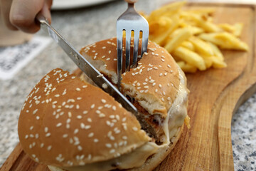 Chef cuts burger in half on wooden board