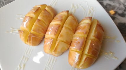 Buttered bread topped with sweetened condensed milk on a white plate.