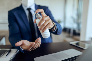 Close-up of businessman disinfecting hands in the office.